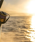 Spinfisher VII 3500 Saltwater Spinning Reel With IPX5 Seal mounted on a boat against a sunrise over the ocean.