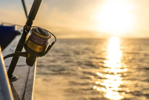 Spinfisher VII 3500 Saltwater Spinning Reel With IPX5 Seal mounted on a boat against a sunrise over the ocean.