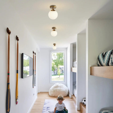 Milk Glass Globe Semi Flush Mount Ceiling Light With Gold Brass Finish Mid Century Modern Style For Hallway Entryway And Bedroom Retro Vibe Brass Ceiling Fixture With Elegant Glass Shade And Contemporary Charm illuminating a modern hallway.