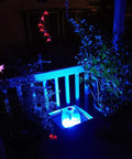 Dope 730 GPH Submersible Pond Pump with RGB ring light illuminating a garden pond at night with surrounding plants
