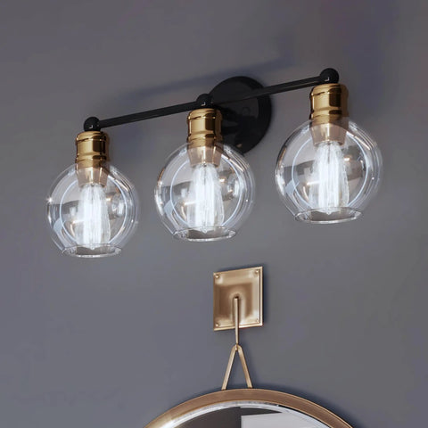 Coastal 3 Light Bath Vanity Light With Clear Glass Globes In Antique Bronze Finish, mounted above a bathroom mirror