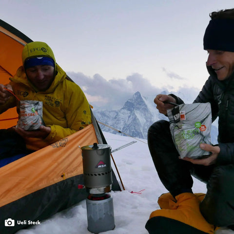 Hikers using Reactor Windproof Camping Stove System With 1.0L Pot Crazy Fast Boil Time For Backcountry Cooking Ideal For Backpacking And Hiking 2024 Version Self Contained All In One Stove Kit in snowy mountain setting.