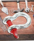 Heavy Duty Galvanized Steel Lifting Shackles Two Pack Iron Strong Hardware Built Tough For Truck Towing Off Road Recovery Quick Release Pin Heavy Load Haulin Operations on wooden surface with tools around.
