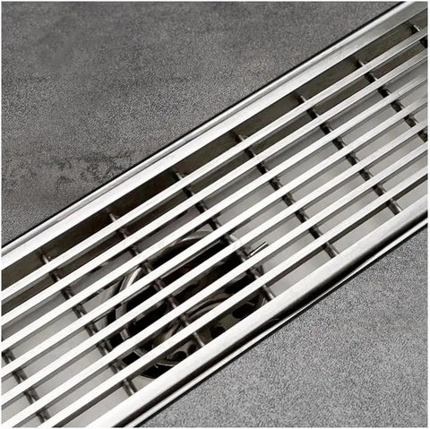 24 Inch Offset Side Outlet Linear Shower Drain In Slick Brushed Stainless Steel Rectangle Design with grate cover and adjustable feet.