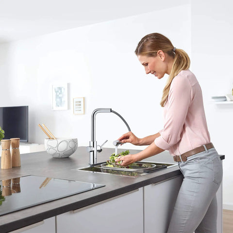 Clean Lines Single Handle Pull Out Kitchen Faucet With Laminar Spray Led Knobs For Chilled Sparkling Water Butter Smooth Pour 180 Swivel Spout in modern kitchen, woman rinsing vegetables.