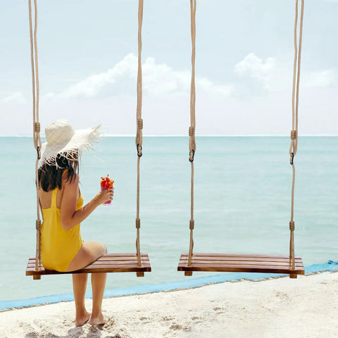 Woman in yellow swimsuit on Two Pack Wood Swing Seats Carbonized Hanging Tree Swing Set With Adjustable Rope by the ocean