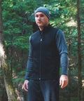 Man wearing Heavy Duty Kick Ass 100 Percent Merino Wool Men Vest Expedition Grade in forest, perfect for outdoor activities.