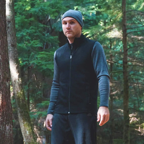 Man wearing Heavy Duty Kick Ass 100 Percent Merino Wool Men Vest Expedition Grade in forest, perfect for outdoor activities.