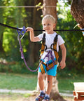 Child using Heavy Duty Trolley Kit With Slackline Pulleys For Backyard Fun, secured on a slackline in a backyard setting