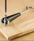 Stainless steel hook being screwed into wooden panel, part of 12 Pack Universal Mount Hooks For Painter Drying Racks, for spray finishing setup.