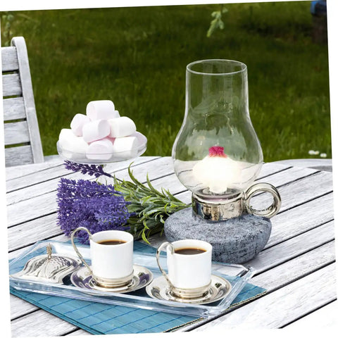 Oil lamp on outdoor table surrounded by flowers, marshmallows, and coffee cups, illustrating 10 Piece Cotton Wick Set For Oil Lamps Kerosene And Propane Lanterns Gas Lamps Outdoor Camping And Tiki Torches Round Design Portable And Easy To Replace Great For Picnics Road Trips And Backyard Gatherings.