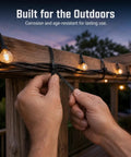 Hands securing Heavy Duty Self Locking Nylon Cable Ties In Black to outdoor lights on wooden deck for weather-resistant cable management.