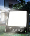 JUDYSSY 6500K Led Floodlight Outdoor, 400W IP68 white security light on green grass, showcasing heat-resistant material.