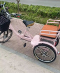 Hassle Free Fold Tandem Tricycle For Adults And Seniors With Rear Bucket Seat And Locking Safety Strap 20 Inch Front Wheel Heavy Duty Steel Frame Bright Pink Chill City Cruisers side view parked with basket.
