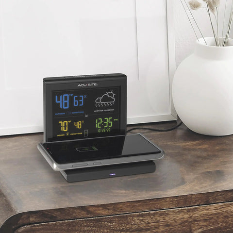 Weather Forecaster Alarm Clock With Wireless Qi Charging Pad Real Time Indoor And Outdoor Temperature And Humidity Calendar Illuminated LCD Display No Wires Needed on a bedside table