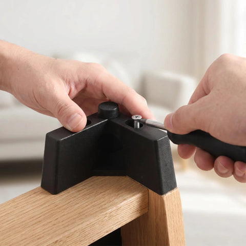 Installing L Shaped Plastic Sofa Legs 4 Pack With M5 Screws using a screwdriver on wooden furniture