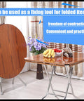 Room with folded wooden table top leaning against folding table, showcasing Four Pack Drop Leaf Table Supports And Folding Hinges Kit With 180 Degree Cross Spring Hinges And Mounting Screws Heavy Duty Iron Die Cast Zinc Plated Built For Durable Kitchen Workshop Or Patio Tables.