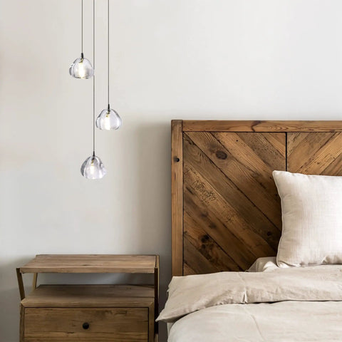 Raindrop Crystal Pendant Lights Set of 3 above wood nightstand with rustic bed, Modern Teardrop Chandeliers in bedroom setting