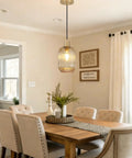 Two Pack Top Tier Amber Cylinder Pendant Lights With Vintage Ribbed Hand Blown Glass And Brushed Gold Adjustable Fixtures serving a dining area.