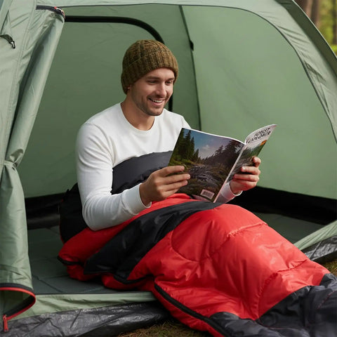 Person sitting in tent using Cozy Cold Weather Sleeping Bag For Adults Perfect For Backpacking And Camping Lightweight And Packable Gear For Hiking Waterproof 190T Polyester Shell Durable Red.