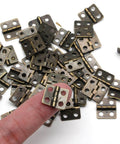 Retro Dope Mini Copper Hinges For Wooden Jewelry Box With 50 Hinges And 200 Replacement Screws, shown in pile, finger for scale.