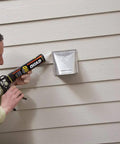 Person applying Beige Window Door And Siding Sealant 10 Oz Tubes Advanced Formula Weatherproof Exterior Caulk to siding