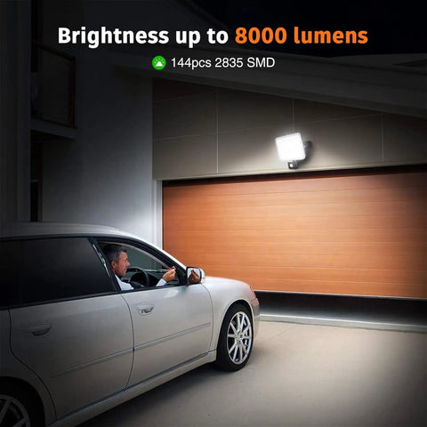 100W Led Floodlights with Motion Sensor, 6000K-6500K Daylight White 80 illuminating a garage driveway with a parked car.