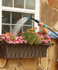 Person using Heavy Duty Swivel Watering Wand for Garden Hose With 5 Spray Patterns to water flowers on window ledge.