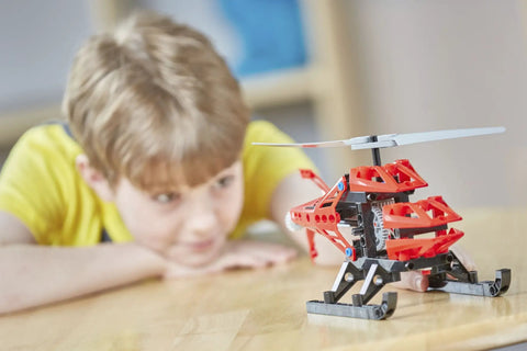 Child playing with rescue copter model from Geared-Up Gadgets 5-In-1 Engineering Kit For Makers on a wooden table.