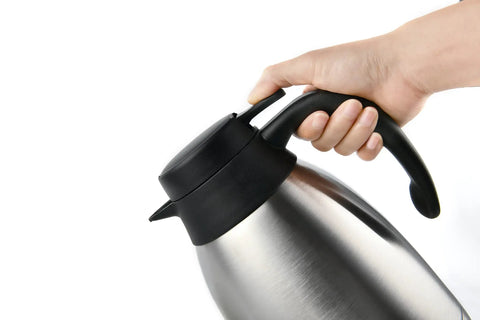 Hand holding stainless steel triple layer vacuum insulated carafe dispenser keeps coffee tea and water piping hot up to 12 hours and extra cold up to 24 hours, 1 liter capacity, durable thermal server for home or office use.