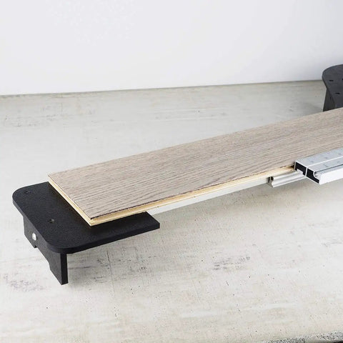 Close-up of Beast Of A 13 Inch Laminate Flooring And Siding Cutter with sliding extension table holding a laminate plank.