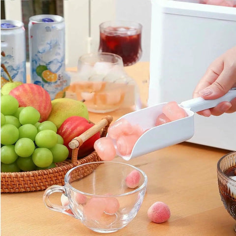 No Fuss Countertop Ice Maker drops nine chill cubes into a clear glass, surrounded by fruit and drinks on a wooden table.