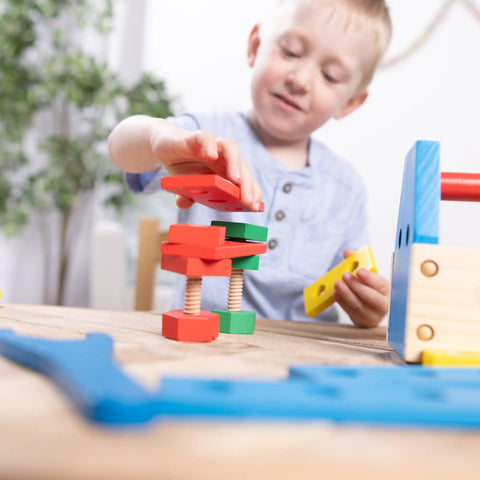 Child playing with Take Along Tool Kit Wooden Construction Toy Set For Little Builders With 24 Pieces including colorful blocks.