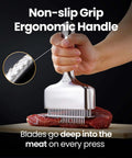 Meat tenderizer tool with long ergonomic handle and stainless steel blade prongs pressing into steak on cutting board