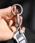 Close-up of Quick Release Titanium Keychain With 2 To 28mm Rings attached to car key, showing swivel mechanism and titanium finish.