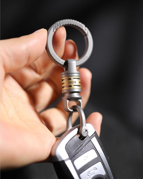 Close-up of Quick Release Titanium Keychain With 2 To 28mm Rings attached to car key, showing swivel mechanism and titanium finish.