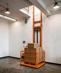 Must-Have Heavy Duty Freight Lift With 2200 Lbs Capacity Electric Cargo Elevator lifting stacked boxes in warehouse.