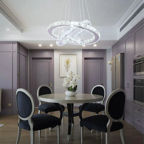 Dimmable LED Three-Ring Chandelier With Crystal Accents And Stainless Steel Pendant Light hanging over a dining table.