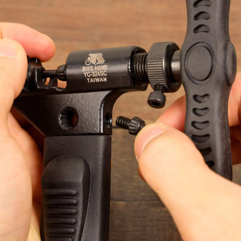 Hands using Pro Grade Bike Chain Rivet And Breaker Tool With Spare Driving Pin for fast, clean pin pushes on single to 12 speed chains