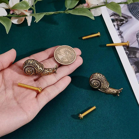 Brass Snail Cabinet Knobs Set Gold Animal Drawer Knobs With Screws Vintage Retro Vibe shown in hand next to a coin