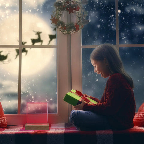 Child with gift box near a window with a 5.9 Inch Wooden LED Light Base Kit Dimmable Colorful Display for holiday decor.