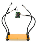 Four Arm Gooseneck Helping Hands Soldering Stand with Steel Weighted Non Slip Base holding a PCB for secure soldering