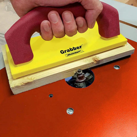Pushblock for Table Saws and Router Tables with Diamond Grip and Non Marring Rubber Bottom Ergonomic Comfort Handle Built Tough Workpiece Holder for Band Saws and Jointers Yellow And Red being used on a router table