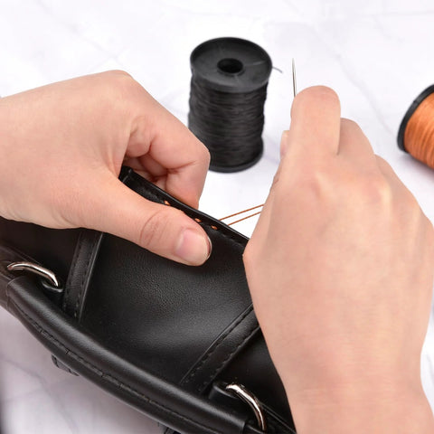 Topus upholstery repair thread kit with heavy-duty needles; hands stitch a black leather bag with black thread