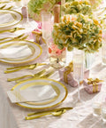 Heavy Duty White Plastic Plates With Gold Trim 175 Piece Bulk Party Essentials set up on a decorated table with silverware and flowers.