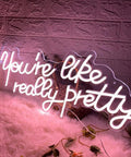 You Are Like Really Pretty Neon Light Sign Peach Pink LED Neon Wall Decor glowing on a fluffy surface in a cozy room setting.