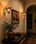 Vintage Glass Wall Sconces Set of 2,Aged Brass Bathroom Vanity Lighting illuminating a wall with amber flower glass shades.