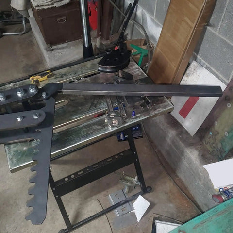Premium Black Oxide Steel Manual Tube And Pipe Bender For Round Square Stock Heavy Duty Hand Bending Tool Ratcheting Handle on workbench.