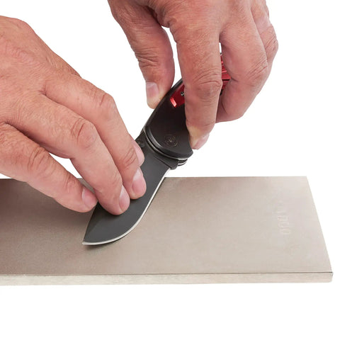 Hands sharpening knife on 8 Inch Diamond Sharpening And Flattening Stone Double Sided 180/600 Grit Bench Stone in home shop.