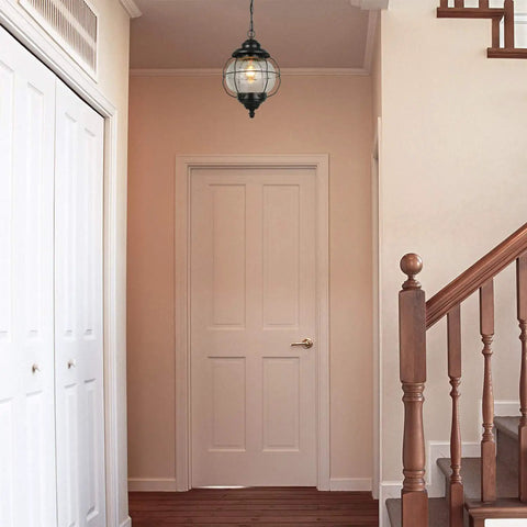 Outdoor Pendant Lights With Farmhouse Style Black Metal Hanging Porch Fixture And Clear Bubbled Glass Globe Inside An Iron Cage Frame For Rustic Vibe Exterior Lantern For Gazebo Patio And Entryway hanging in hallway.